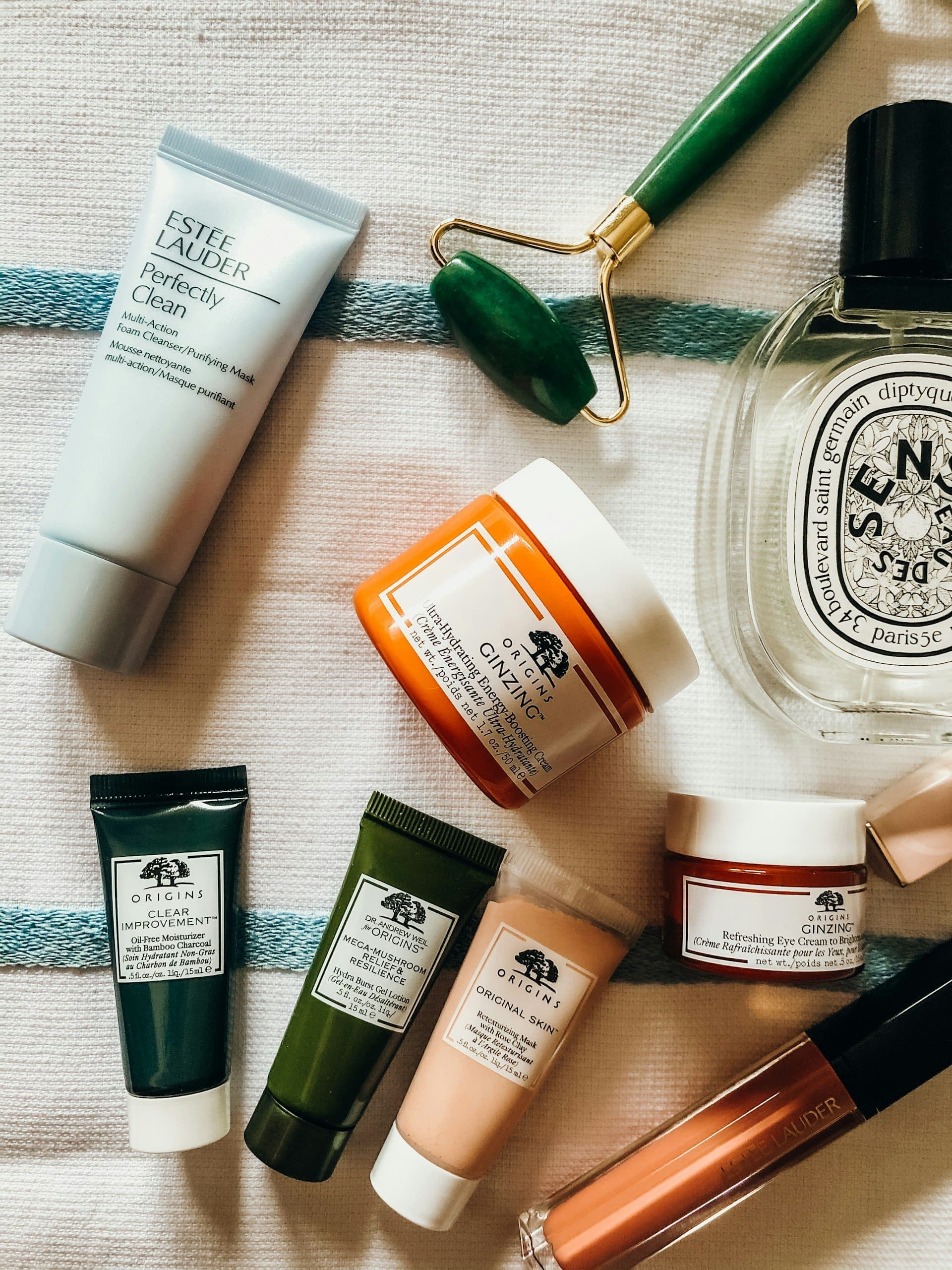 Skincare bottles and botanicals arranged on a warm ivory surface